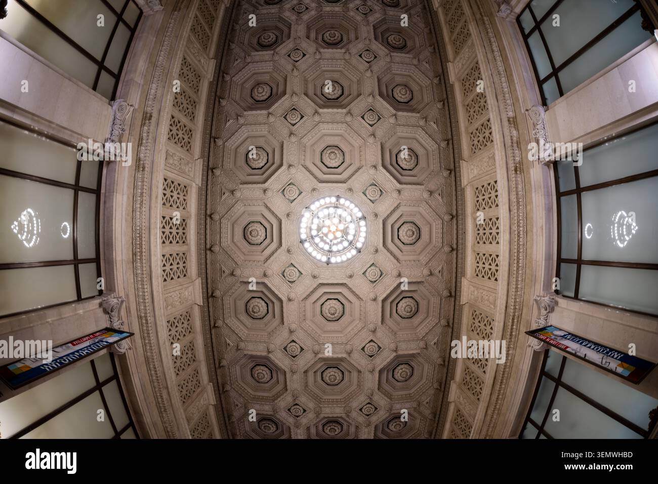 National Postal Museum soffitto della hall a cassettoni Oculus Fisheye Washington DC | WASHINGTON D.C., Stati Uniti - Una vista a fisheye curva il soffitto in gesso a cassettoni della hall principale del National Postal Museum in un campo ovale di pannelli ottagonali e rosette scolpite convergenti su un oculus centrale. Lo schema appartiene al programma ornamentale Beaux-Arts del City Post Office Building, progettato dall'azienda Daniel H. Burnham e completato intorno al 1914, adattando una griglia di casseforti i costruttori romani una volta utilizzati per alleggerire volte e cupole. Foto Stock