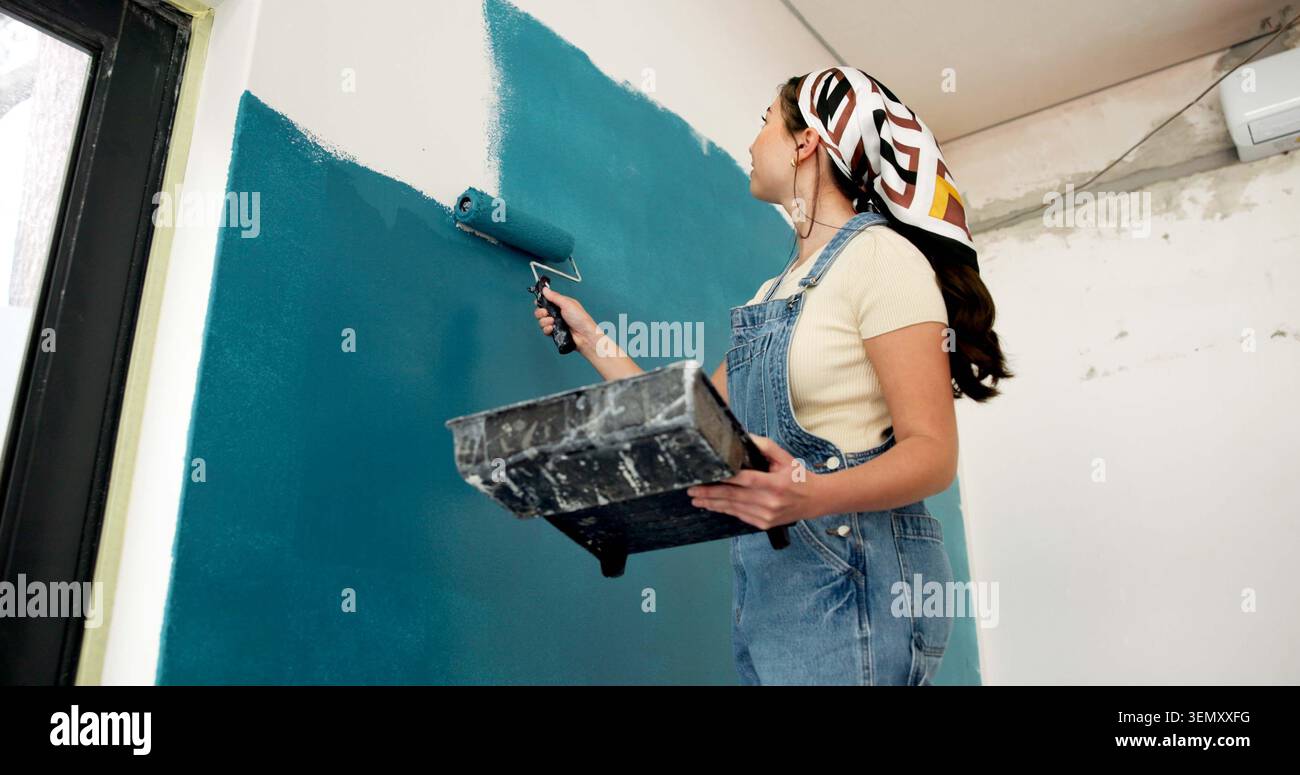 Donna, rullo e parete verniciata con lavori di ristrutturazione, creativo e ad angolo basso per lo sviluppo di proprietà. Persona, design degli interni e attrezzature con corsa Foto Stock