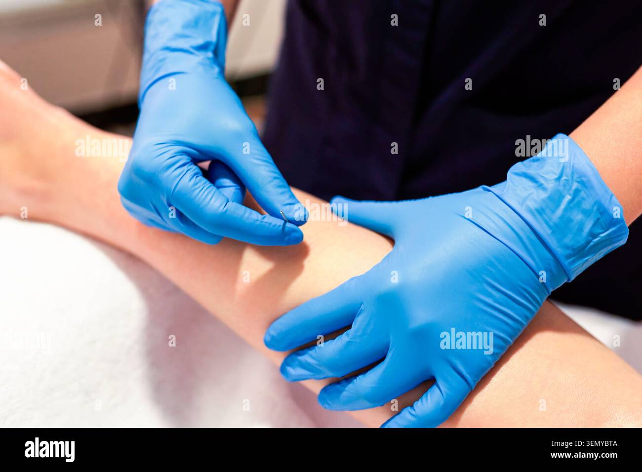 Fisioterapista che esegue la terapia manuale delle gambe con guanti blu Foto Stock