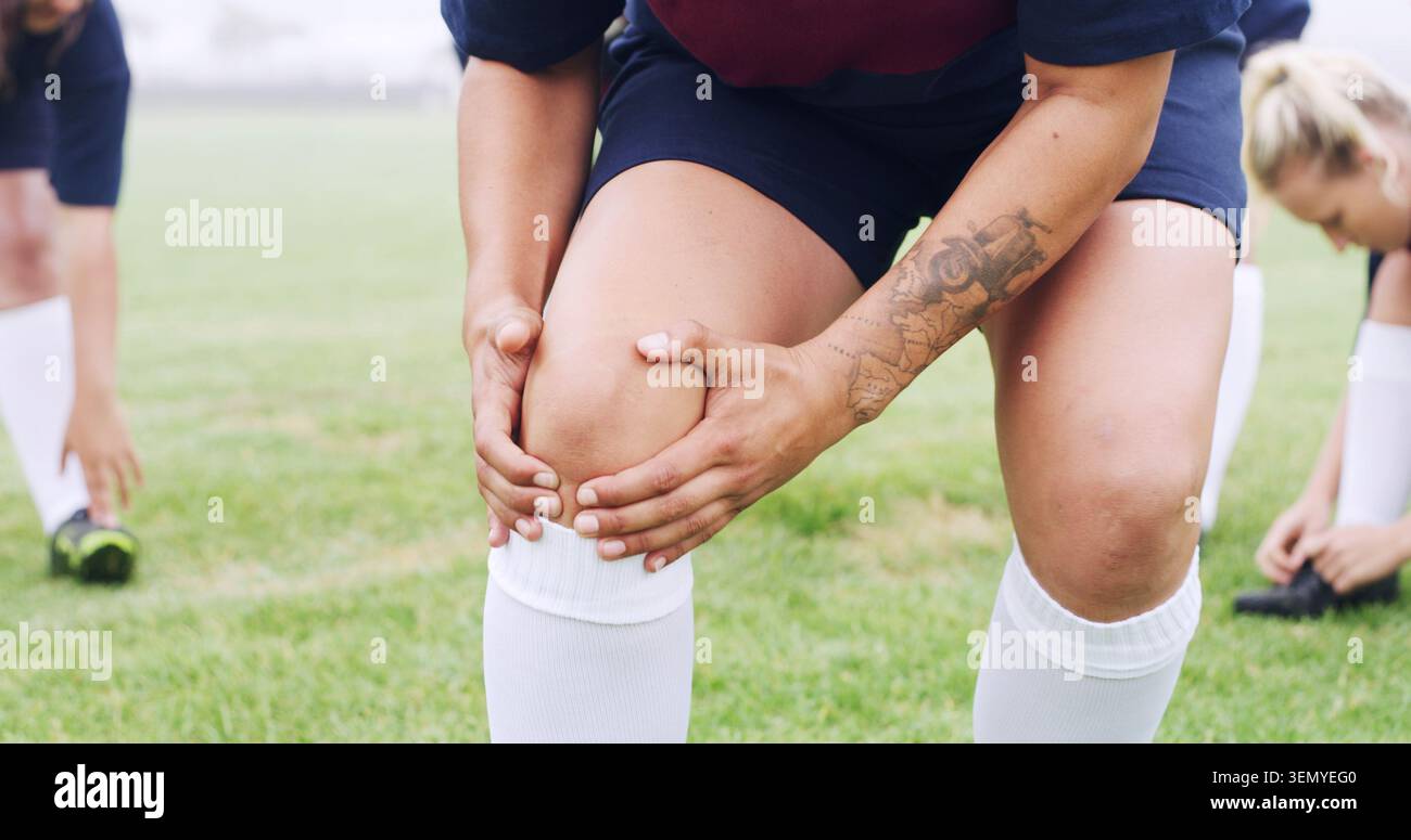 Ginocchio, dolore e rugby con mani di donna sul campo per lesioni sportive, infiammazione e tensione. Allenamento incidente, atleta emergenza e tensione con Foto Stock