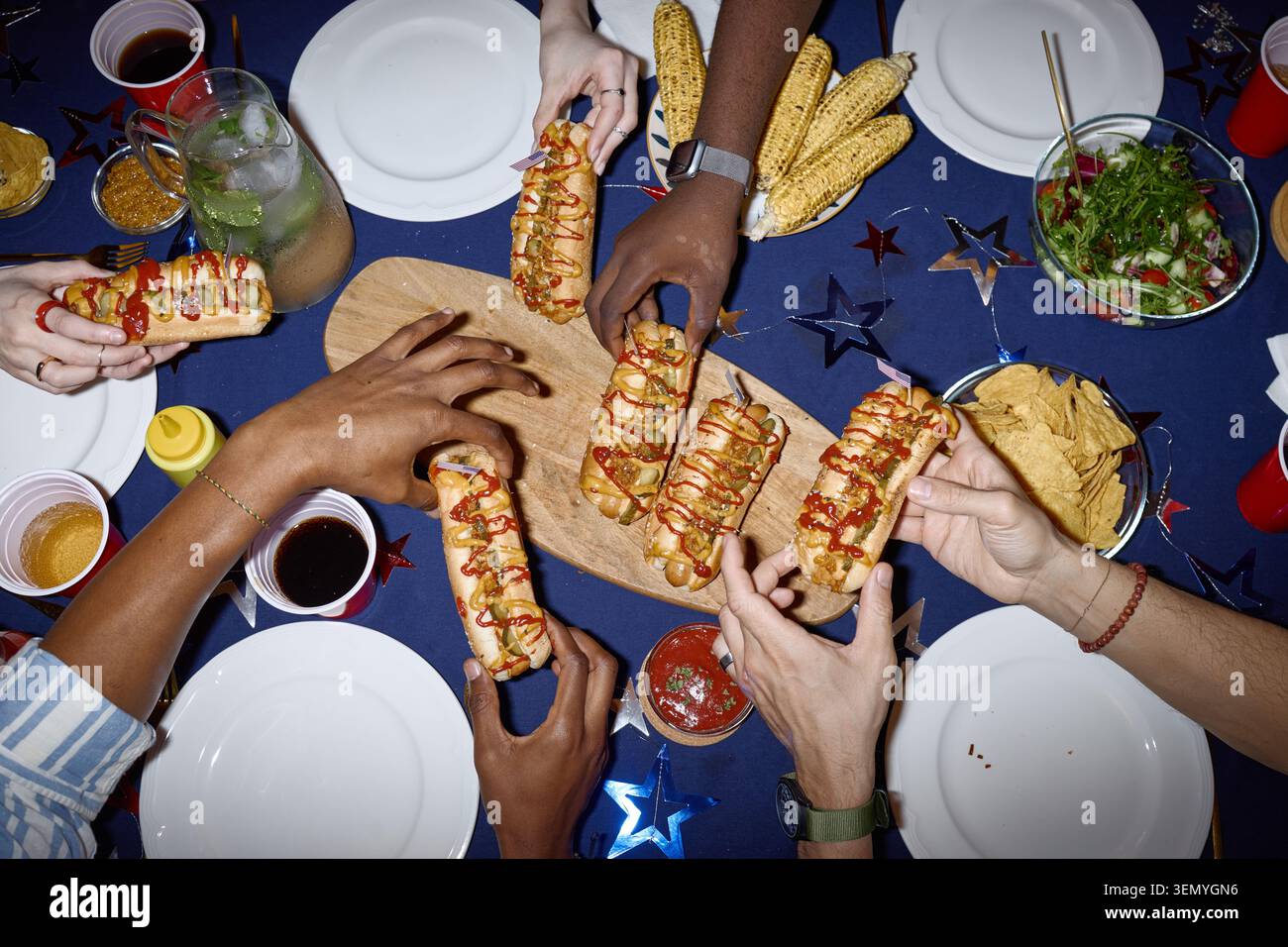 Amici adulti diversi che si occupano di Hot Dogs a Home Holiday Cookout Foto Stock