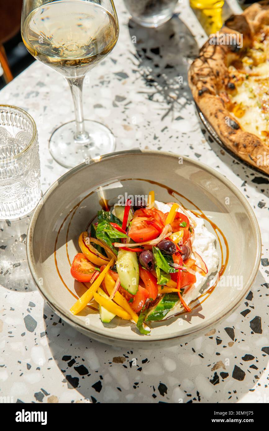 Insalata fresca e vino in un vivace ambiente all'aperto, perfetto per una giornata di sole Foto Stock