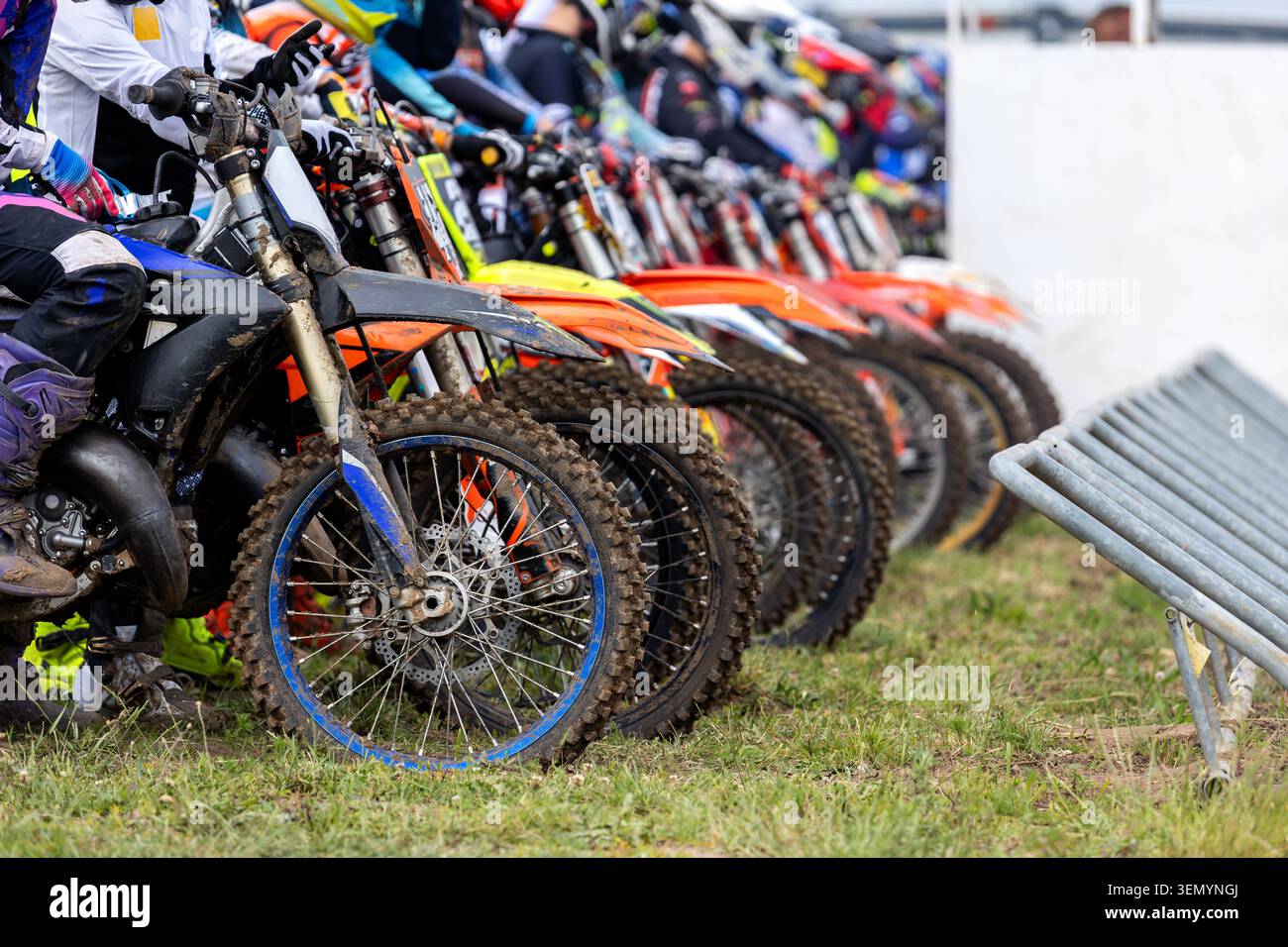 I piloti di Motocross si allineano prima di iniziare una gara competitiva su pista all'aperto. Attrezzature protettive per le macchine coperte di fango gli atleti creano un'atmosfera di velocità Foto Stock