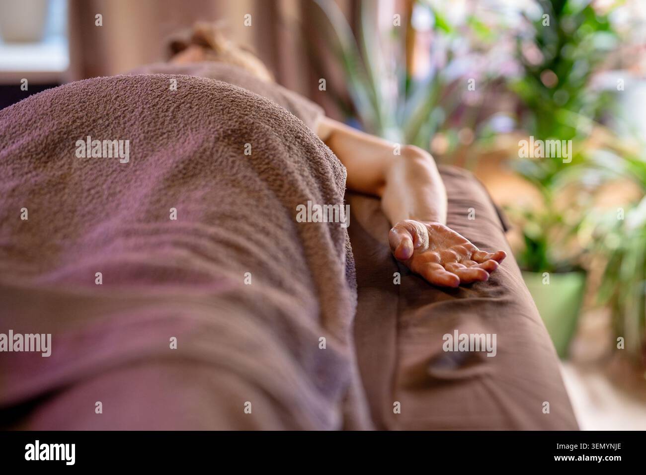 Paziente donna sdraiata sul letto spa in un lussuoso salone di bellezza coperto di asciugamano che si rilassa dopo un massaggio corpo. Foto Stock