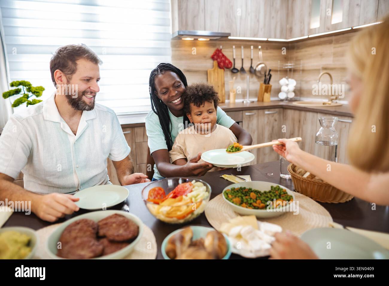 Una famiglia gioiosa condivide una vasta gamma di piatti in un ambiente caldo da cucina. Foto Stock