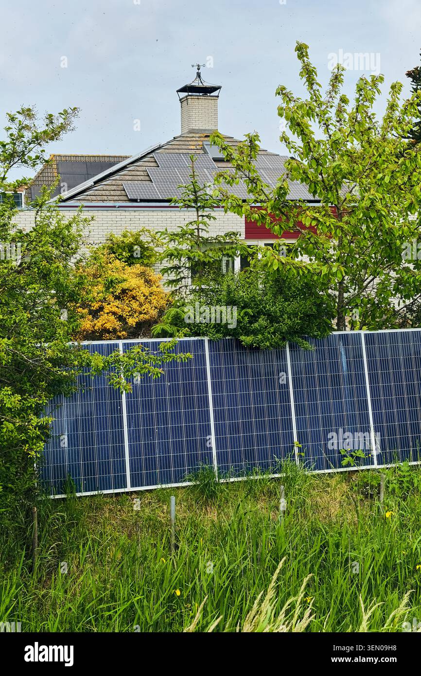 Soluzioni energetiche sostenibili: Pannelli solari su un tetto residenziale e un impianto di terra a Den Oever, paesi bassi, per una vita verde Foto Stock