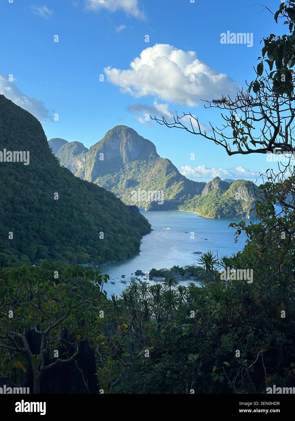 Una baia turchese si snoda tra ripide vette tropicali, creando un passaggio insulare nascosto sotto nuvole brillanti Foto Stock