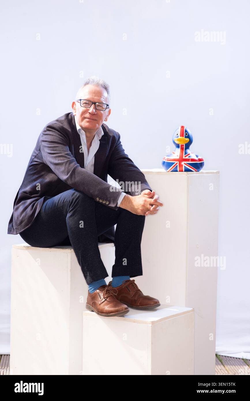 Fintan o'Toole si erge accanto a un'anatra di gomma dipinta nei colori della bandiera britannica. Si appoggia su un piedistallo bianco. Foto Stock