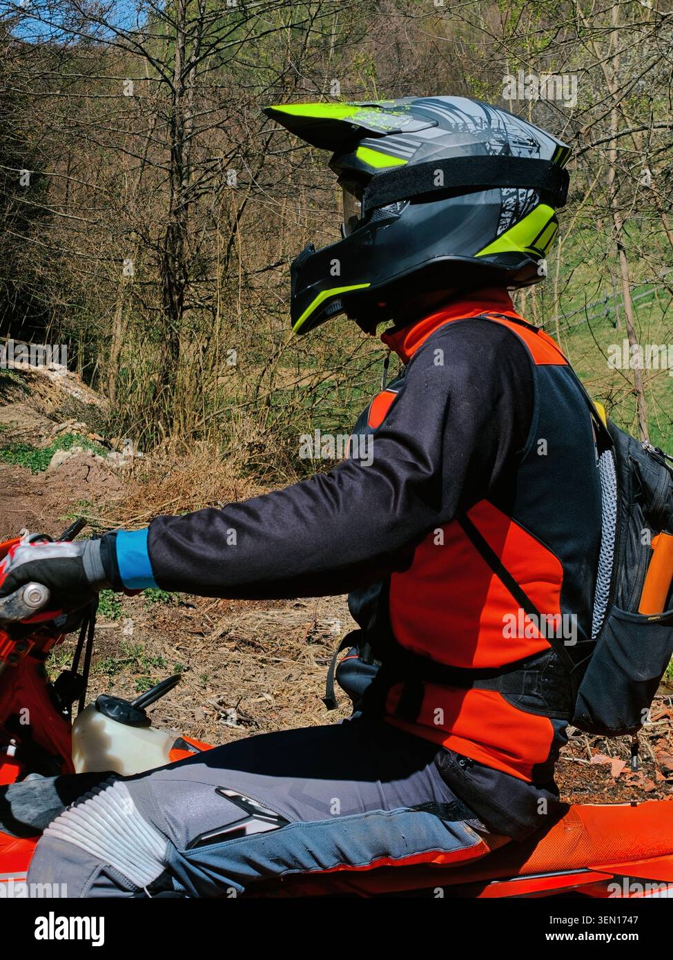 Guida fuoristrada che indossa casco e attrezzatura protettiva su Red Dirt Bike in Forest Trail Foto Stock