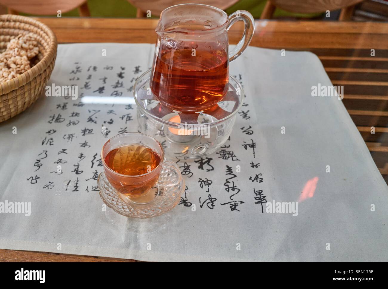 Tè fermentato Jangheung Cheongtaejeon in una pentola di vetro, accanto al suo unico blocco invecchiato a forma di moneta su un panno calligrafico, che mostra la cultura asiatica. Foto Stock