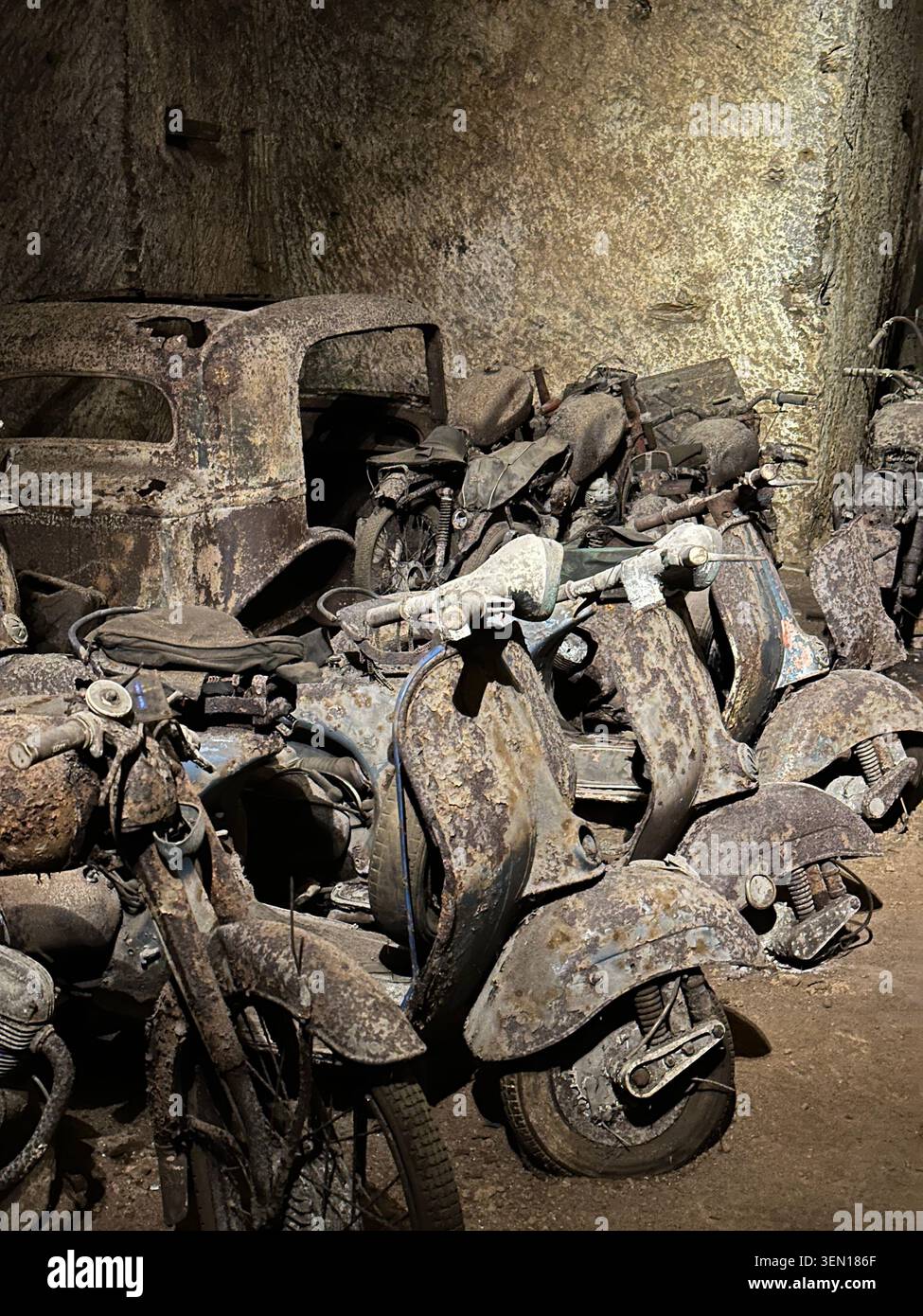WW2- Scooter, pezzi di scooter polverosi si intrecciano in un angolo dimenticato dell'officina, un cimitero meccanico di ruggine, gomma e vernice sbiadita. - Immagine stock catturata con smartphone