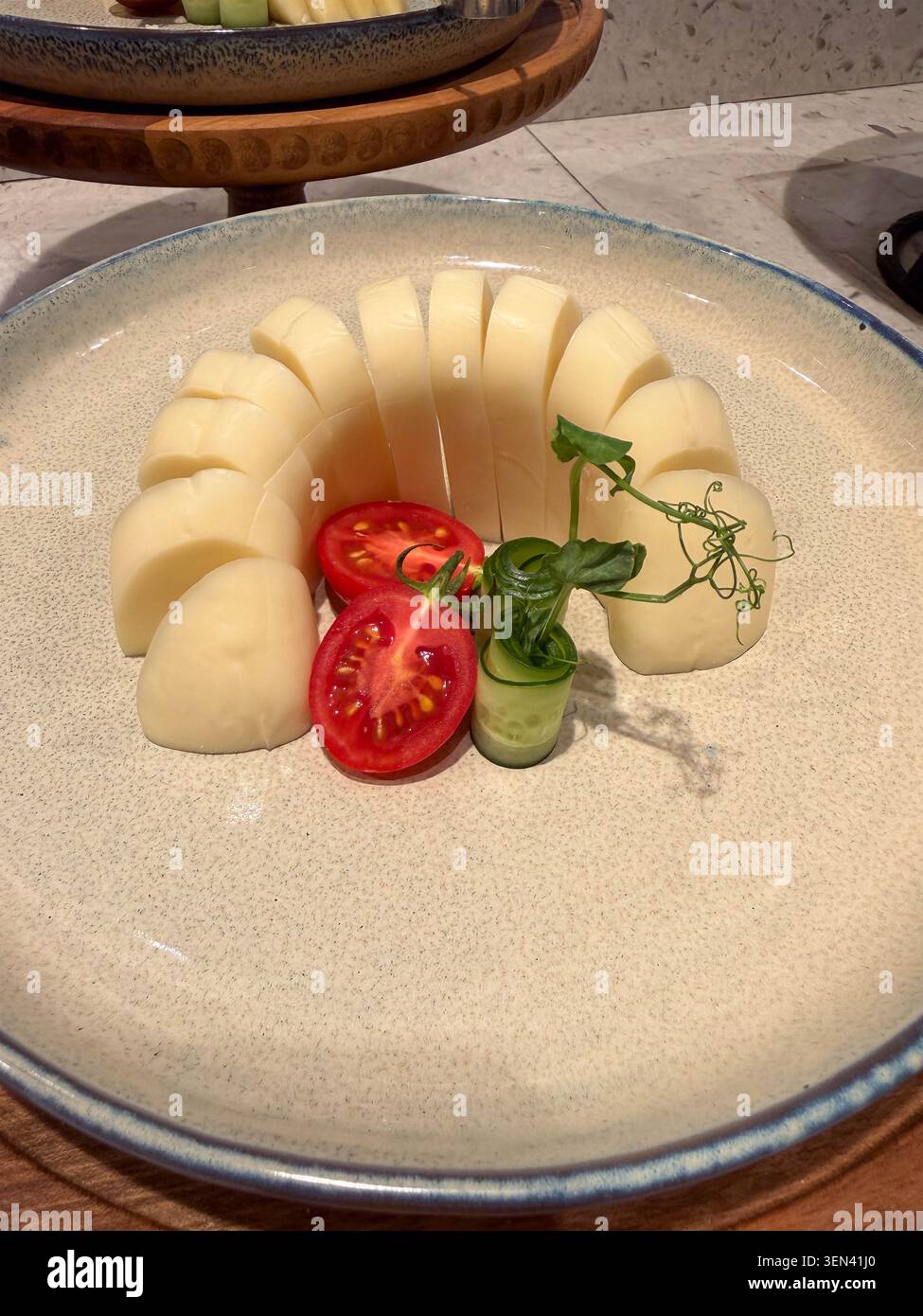 Formaggio semiduro a fette con pomodori ciliegini e germogli di pisello su un piatto di ceramica Foto Stock