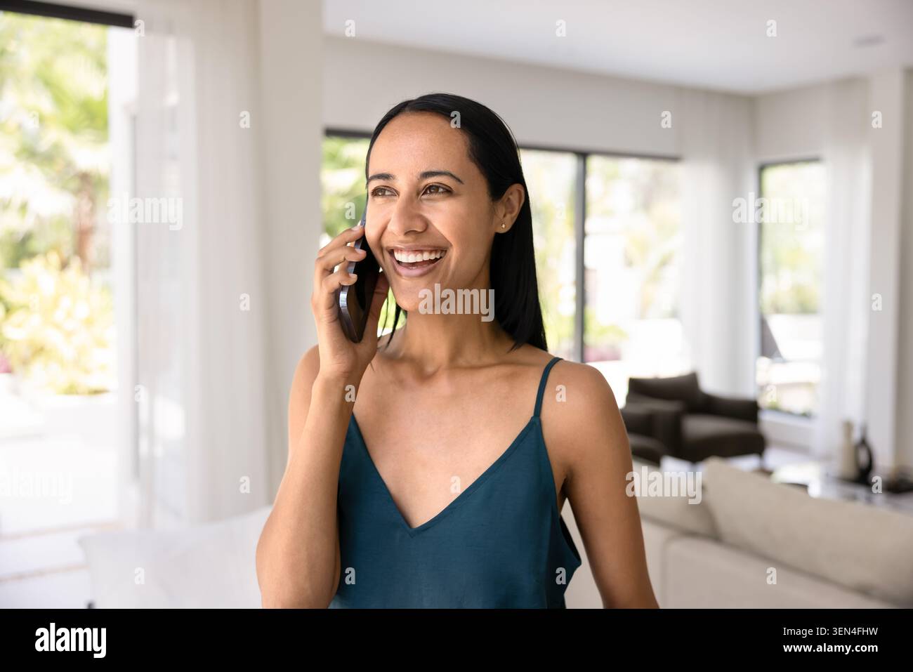 Giovane donna che parla con lo smartphone a casa Foto Stock