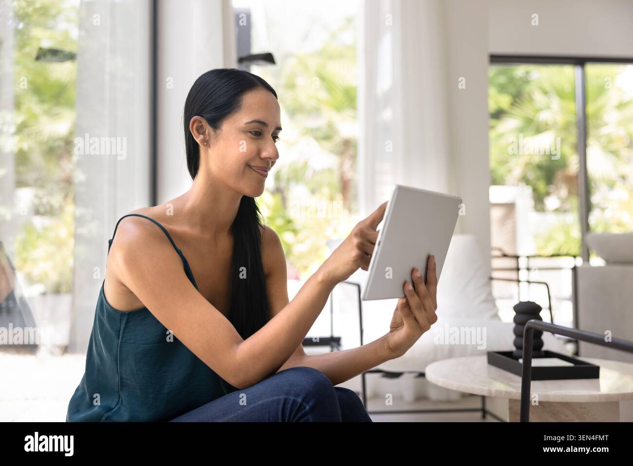 Donna che usa un tablet digitale nel salotto moderno Foto Stock