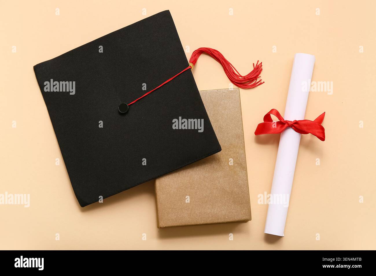 Diploma con nastro rosso, libro e cappello graduato su sfondo beige Foto Stock