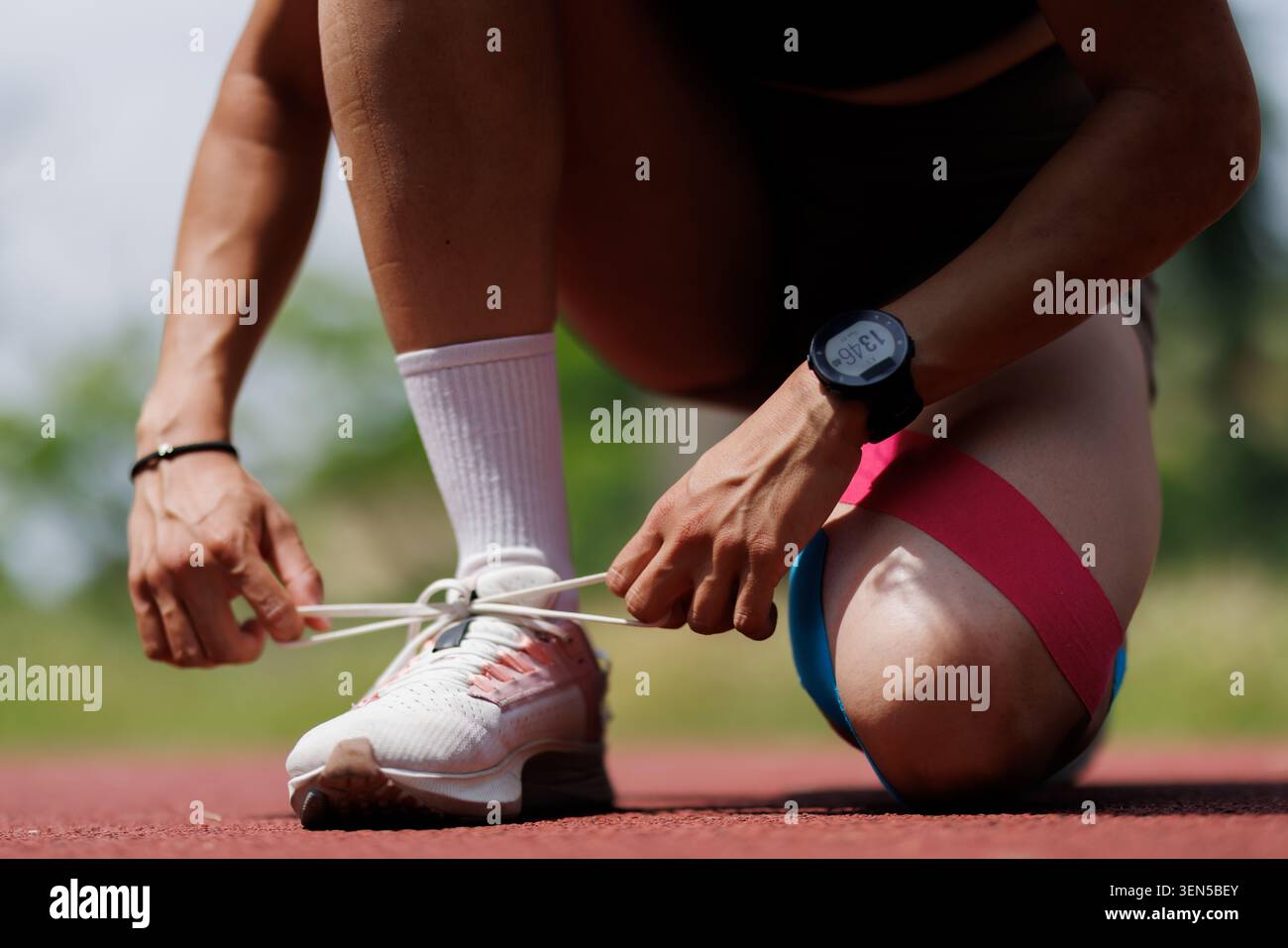Atleta che si prepara per una corsa legando scarpe all'aperto in pista Foto Stock