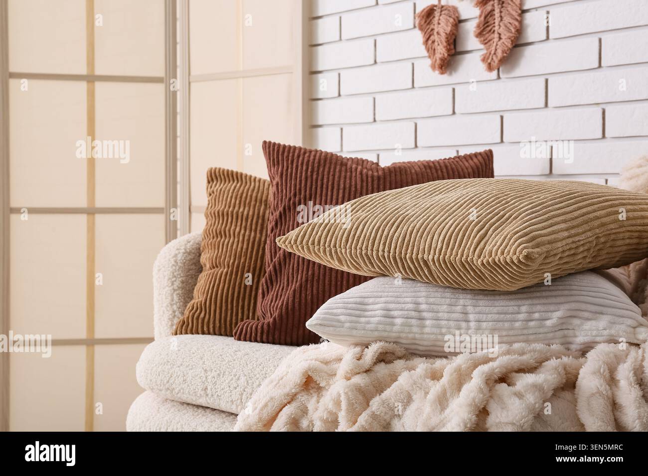 Interni accoglienti con cuscini in velluto a coste e soffice coperta su un comodo divano, arredi moderni del soggiorno Foto Stock