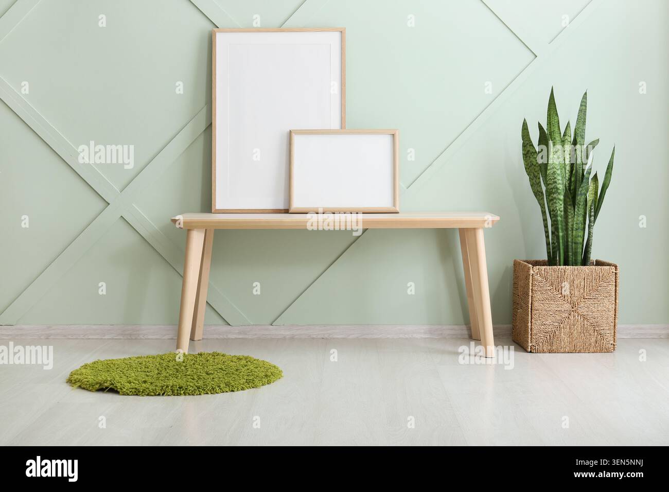 Interni dal design moderno con cornici bianche, panca in legno, impianto di serpenti e decorazioni a parete verdi Foto Stock