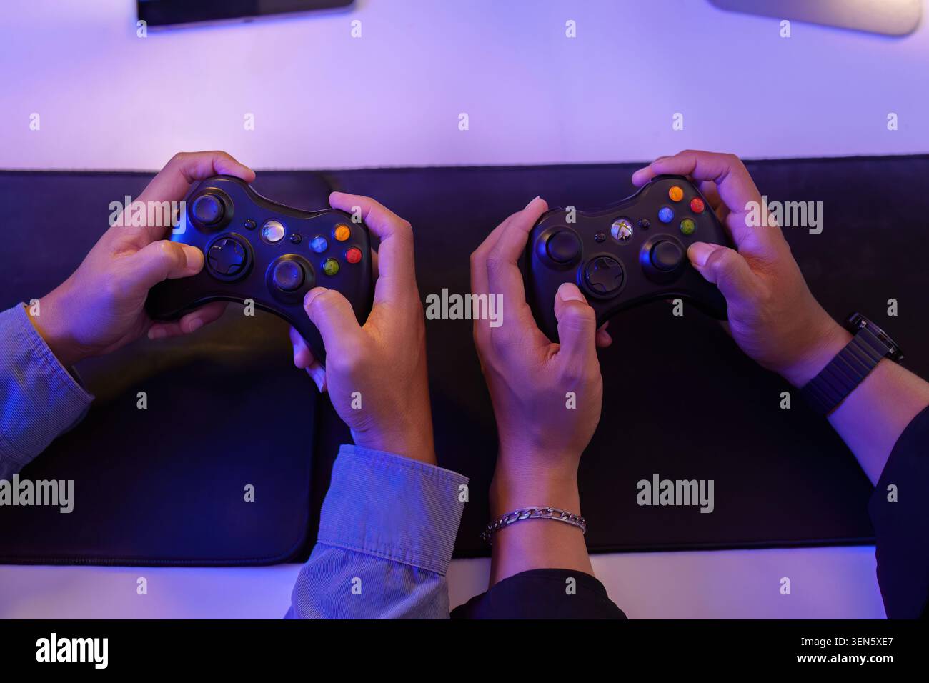 Vista dall'alto dei controller di videogiochi con le mani in mano per la tecnologia di eSport per il gaming e due persone che giocano Foto Stock