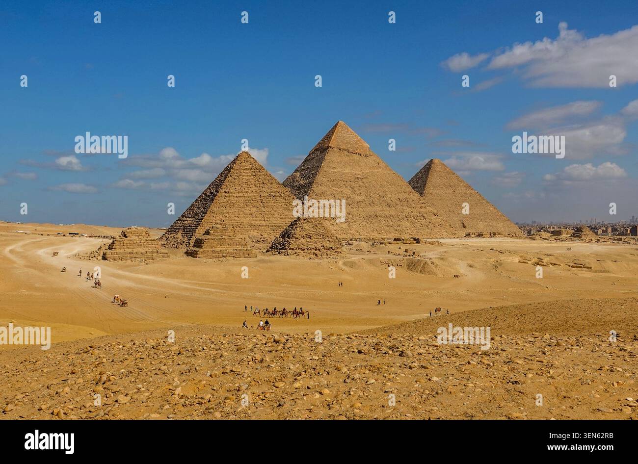 Complesso piramidale di Giza dal punto panoramico con treni a cammello e skyline del Cairo: piramidi di Menkaure, Khafre e Khufu. Egitto, 17 febbraio 2024 Foto Stock