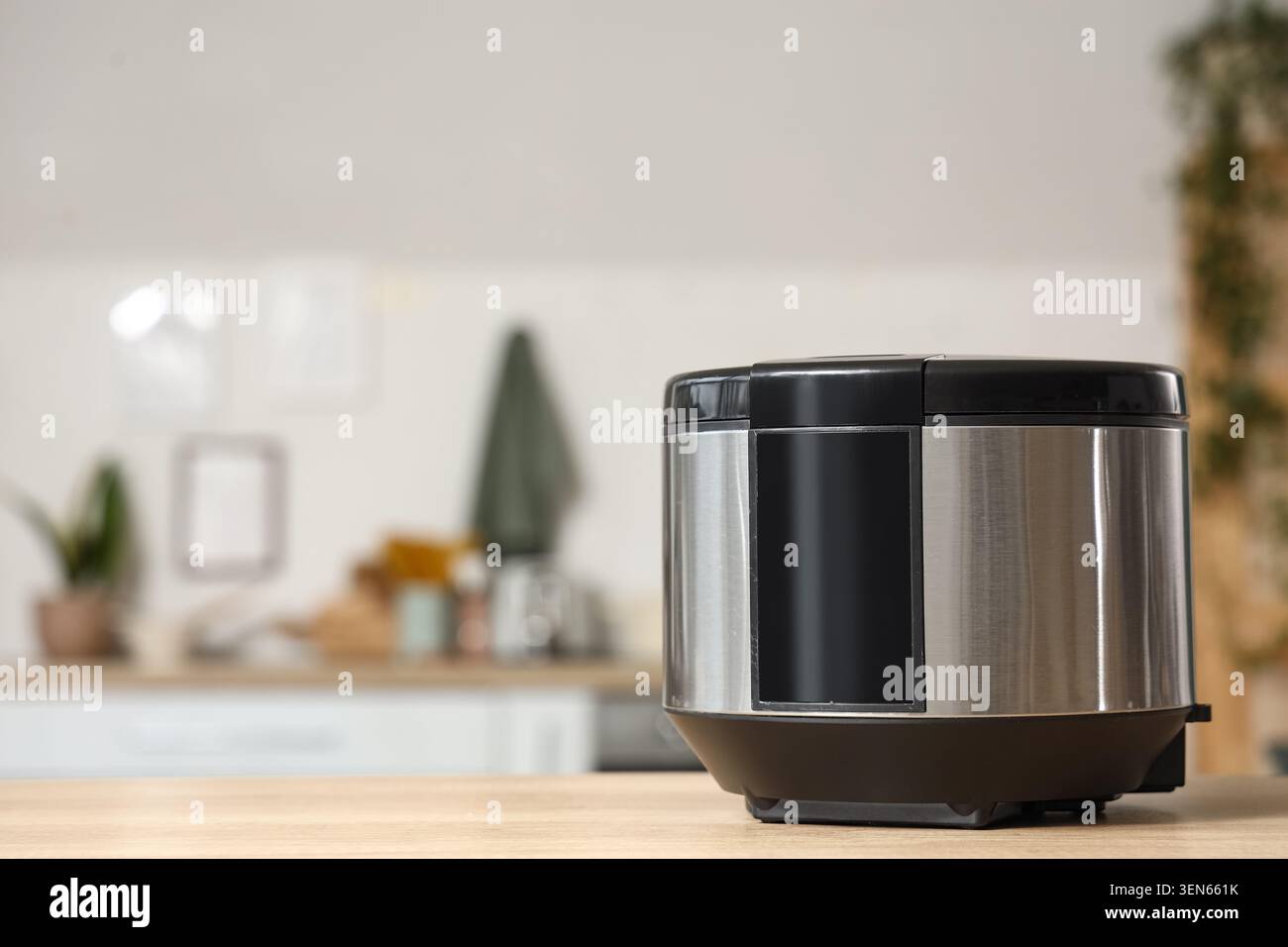 Moderno cuoci riso in acciaio inox su ripiano in legno della cucina, apparecchio di cottura casalingo per pasti sani Foto Stock