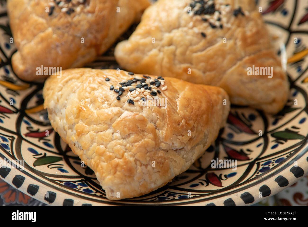 Pasticceria orientale salata fatta in casa con semi di sesamo bianco e nero, vista dall'alto. Vista dall'alto del cibo a base di torte. Vista dal piano d'esame. Torta triangolare di Samsa con carne Foto Stock