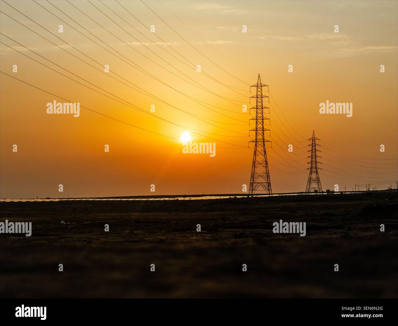 Torri di trasmissione ad alta tensione e impianti solari al tramonto, infrastrutture per le energie rinnovabili e rete di distribuzione dell'energia elettrica Foto Stock