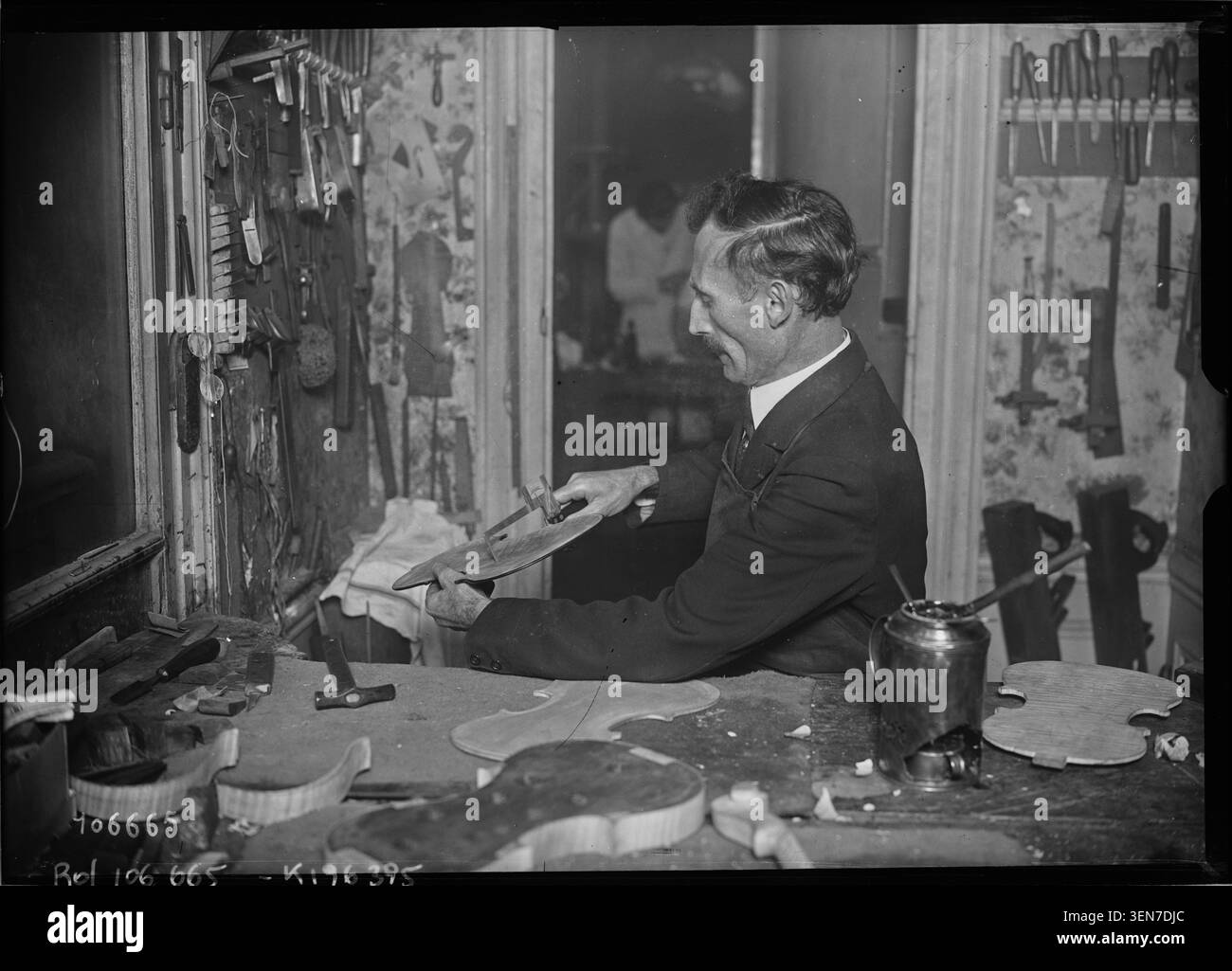 Una fotografia di stampa registra l'attività svolta in un'officina di liuteria in cui i liutai lavorano per la realizzazione o la riparazione di strumenti. L'immagine documenta le tecniche artigianali e l'ambiente di laboratorio in Francia. Foto Stock