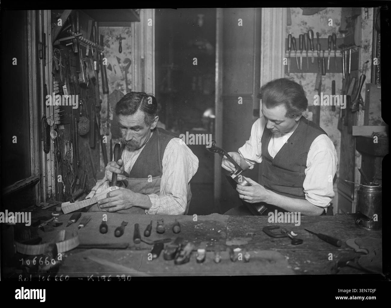 Una fotografia di stampa del 1926 registra un laboratorio di liuteria in Francia, dove i liutai lavorano nella lavorazione e riparazione di violini, documentando la produzione artigianale e la costruzione di strumenti musicali. Foto Stock
