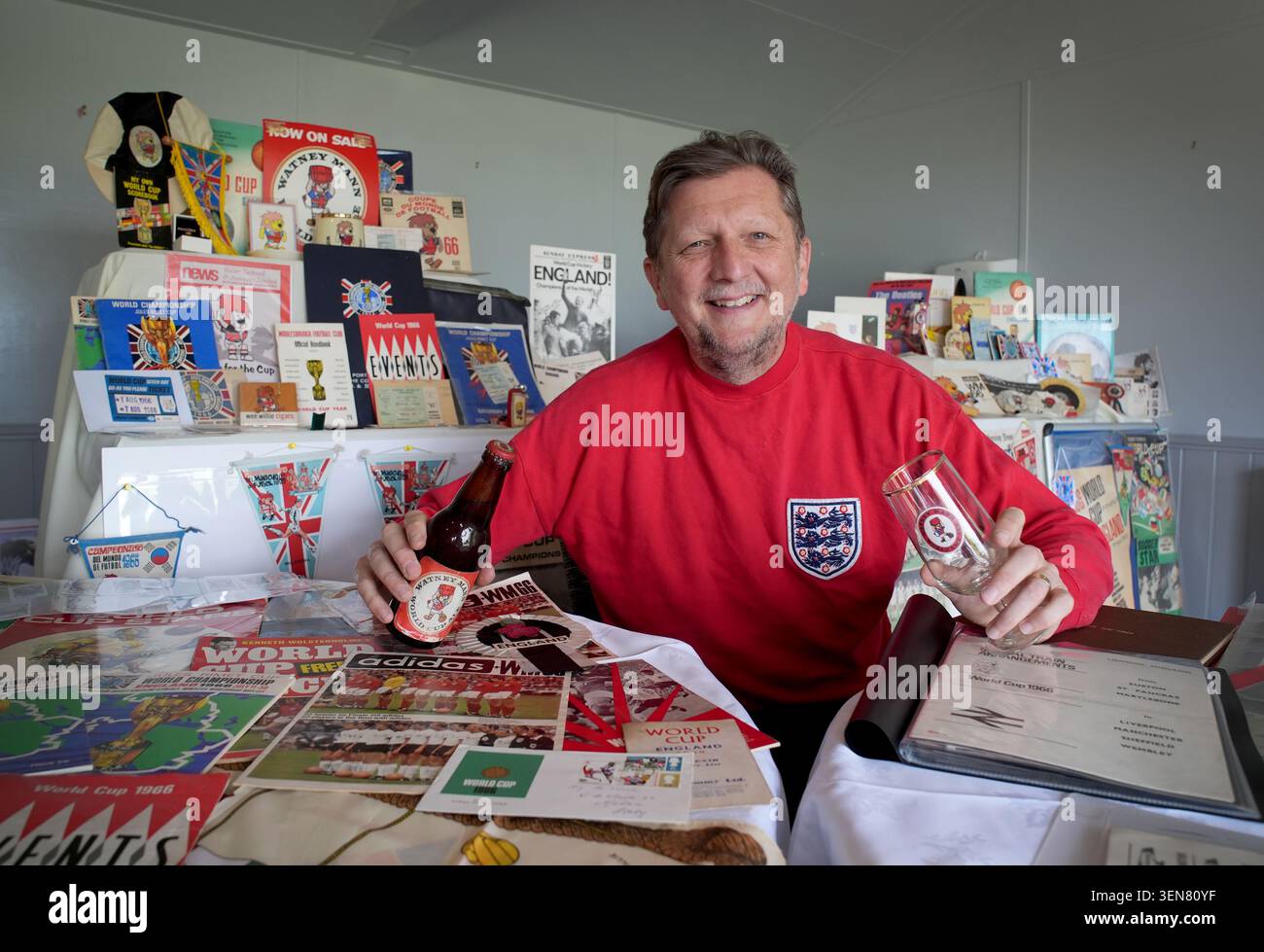 Stephen Holt, 55 anni, con la sua collezione di cimeli della Coppa del mondo 1966 durante un evento Care Home Open Week presso la casa di cura di Halden Heights ad Ashford, nel Kent. Il preside in pensione Holt, è rimasto affascinato dall'unico trionfo della Coppa del mondo d'Inghilterra sin da bambino e ha iniziato ad accumulare una birra ricordo di 60 anni per festeggiare se quest'anno l'Inghilterra vince il torneo. Data foto: Mercoledì 10 giugno 2026. Foto Stock