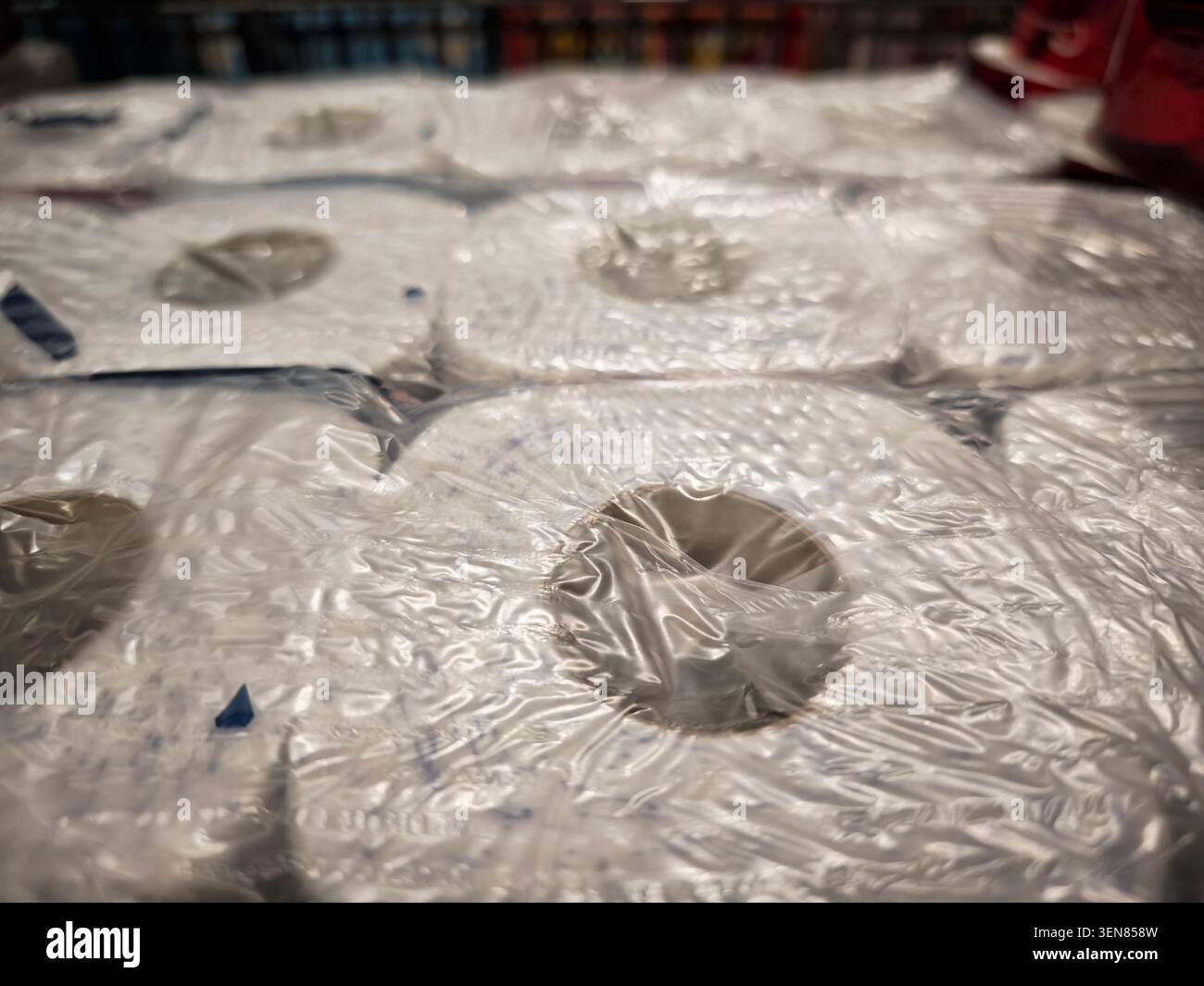 I rotoli di plastica sono impilati in modo ordinato su un tavolo in un vano portaoggetti accanto agli articoli da cucina, pronti per l'uso nella preparazione degli alimenti. Foto Stock