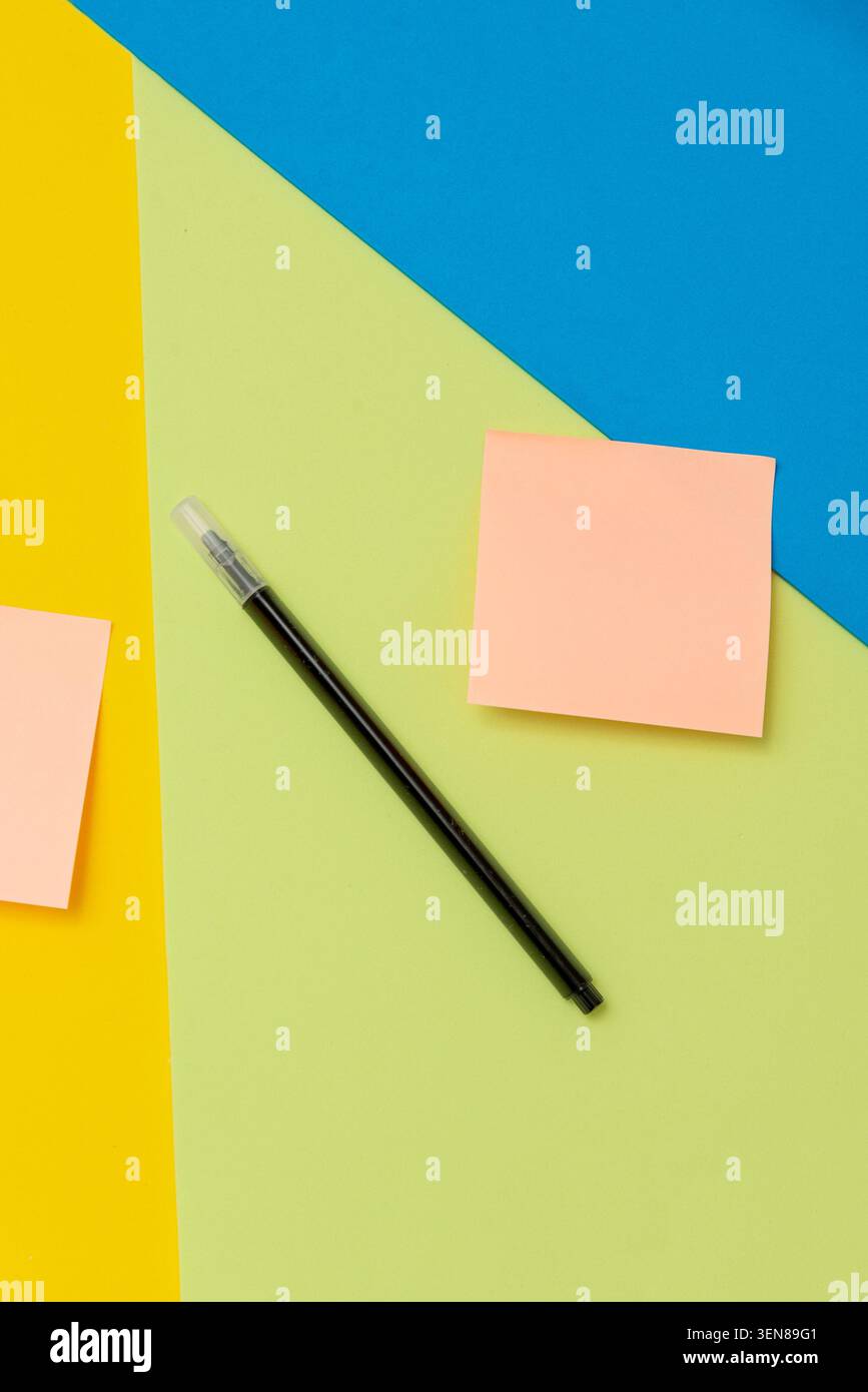 Penna nera in feltro e adesivi bianchi con spazio di copia per il testo su sfondo giallo verde e blu Foto Stock