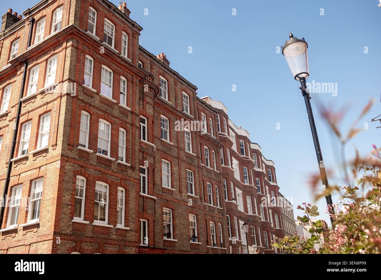 LONDRA - 22 APRILE 2026: KENSINGTON W8 - esclusivo edificio residenziale vittoriano in mattoni rossi, esterno sotto cieli azzurri, nella zona di Londra Foto Stock