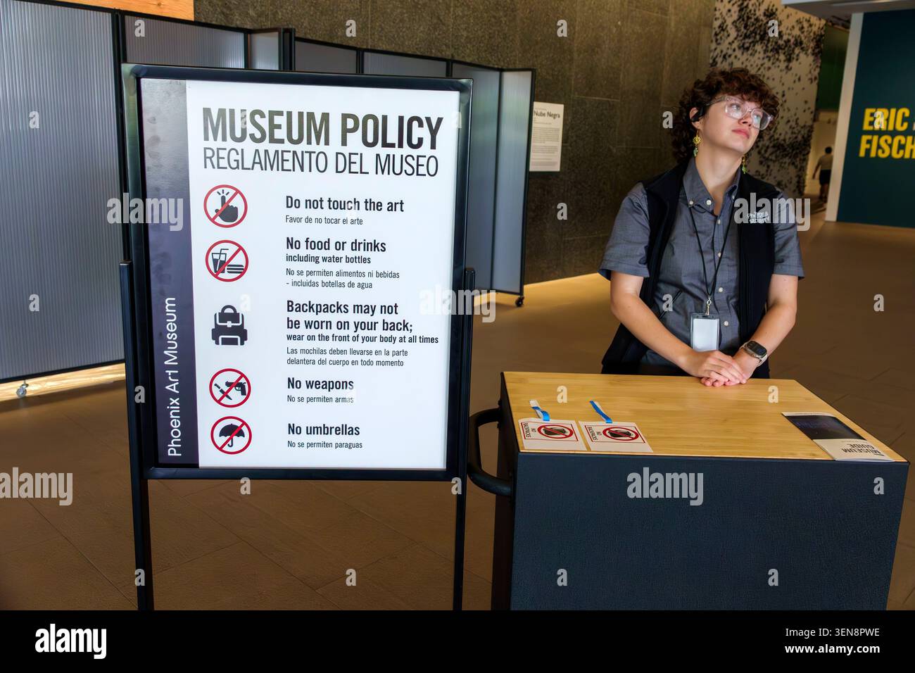 Phoenix, Arizona, Phoenix Art Museum, Central Arts District, cartello con la politica del museo, banco di sicurezza, dipendente del museo, donna adulta, membro del personale, servizio visitatori Foto Stock