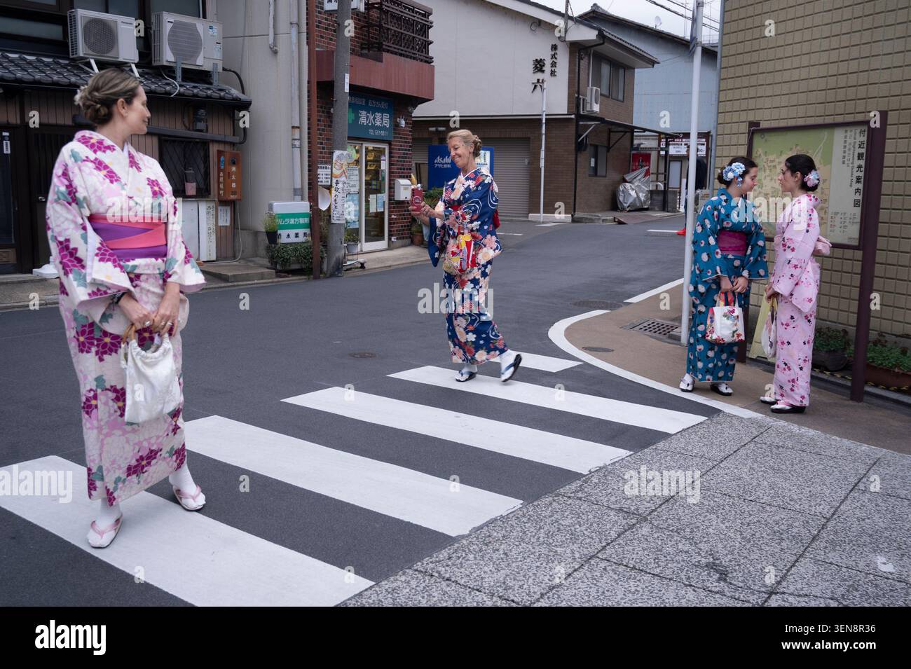 Giappone, Kyoto aprile 2026. Le madri e le figlie occidentali che indossano kimono posano per le foto su un incrocio zebrato Foto Stock