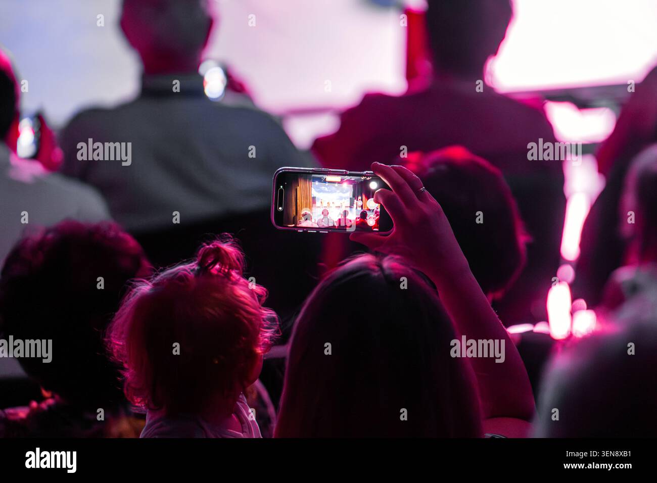 Lo spettatore filma un colorato spettacolo di danza sul palco utilizzando un telefono cellulare. Foto Stock