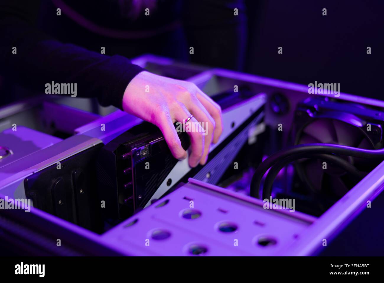 Una giovane videogamer aggiorna il suo PC per videogame con una nuova scheda grafica in una configurazione con luce viola Foto Stock