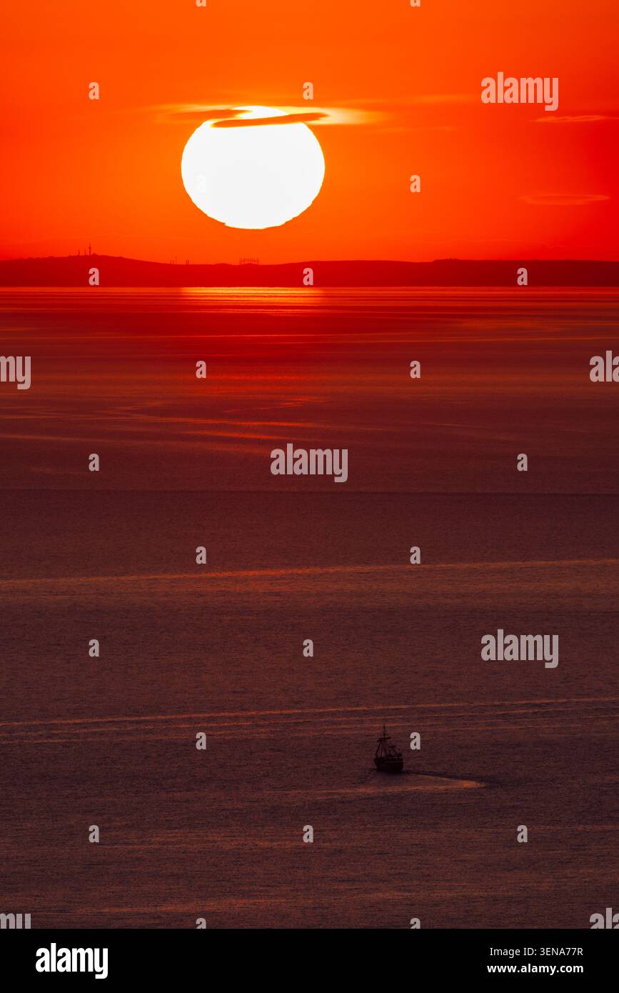 Naviga sotto il sole luminoso sul mare calmo allo spettacolare tramonto arancione Foto Stock