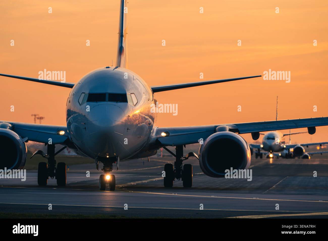Linea di aerei passeggeri che rullano sulla pista dell'aeroporto per il decollo durante le ore di punta al tramonto dorato. Aviazione, congestione dei voli commerciali, aria Foto Stock