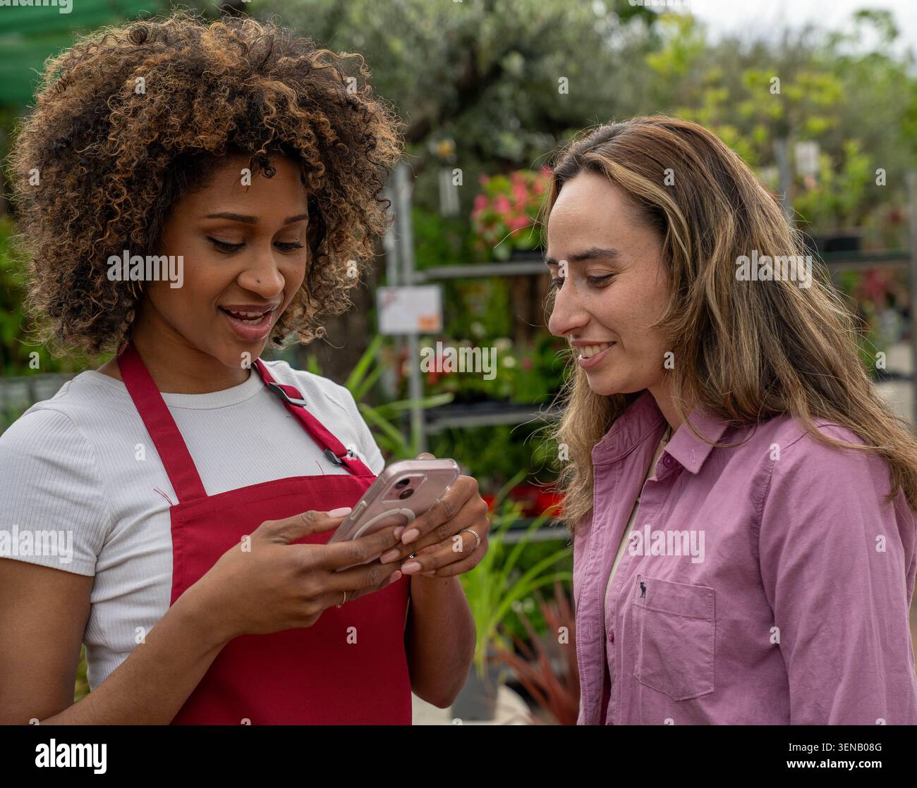 Due donne che controllano uno smartphone in un giardino Foto Stock