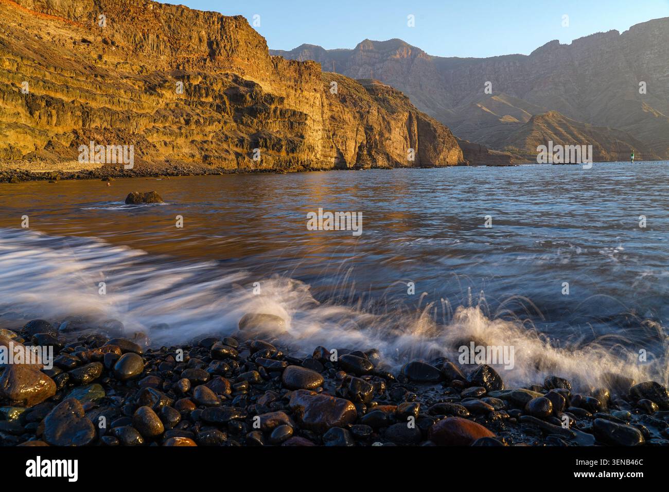 Tramonto dorato sulle scogliere vulcaniche e sulla costa rocciosa vicino a Puerto de las Nieves, Gran Canaria, Isole Canarie, Spagna Foto Stock