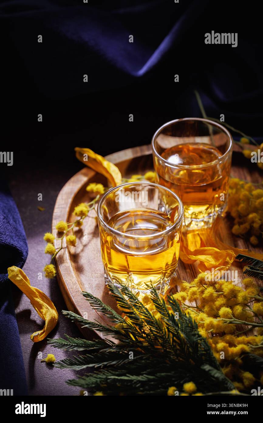 Whisky o brandy bicchieri con Mimosa Flowers e Petals Spring Alcohol STILL Life Foto Stock