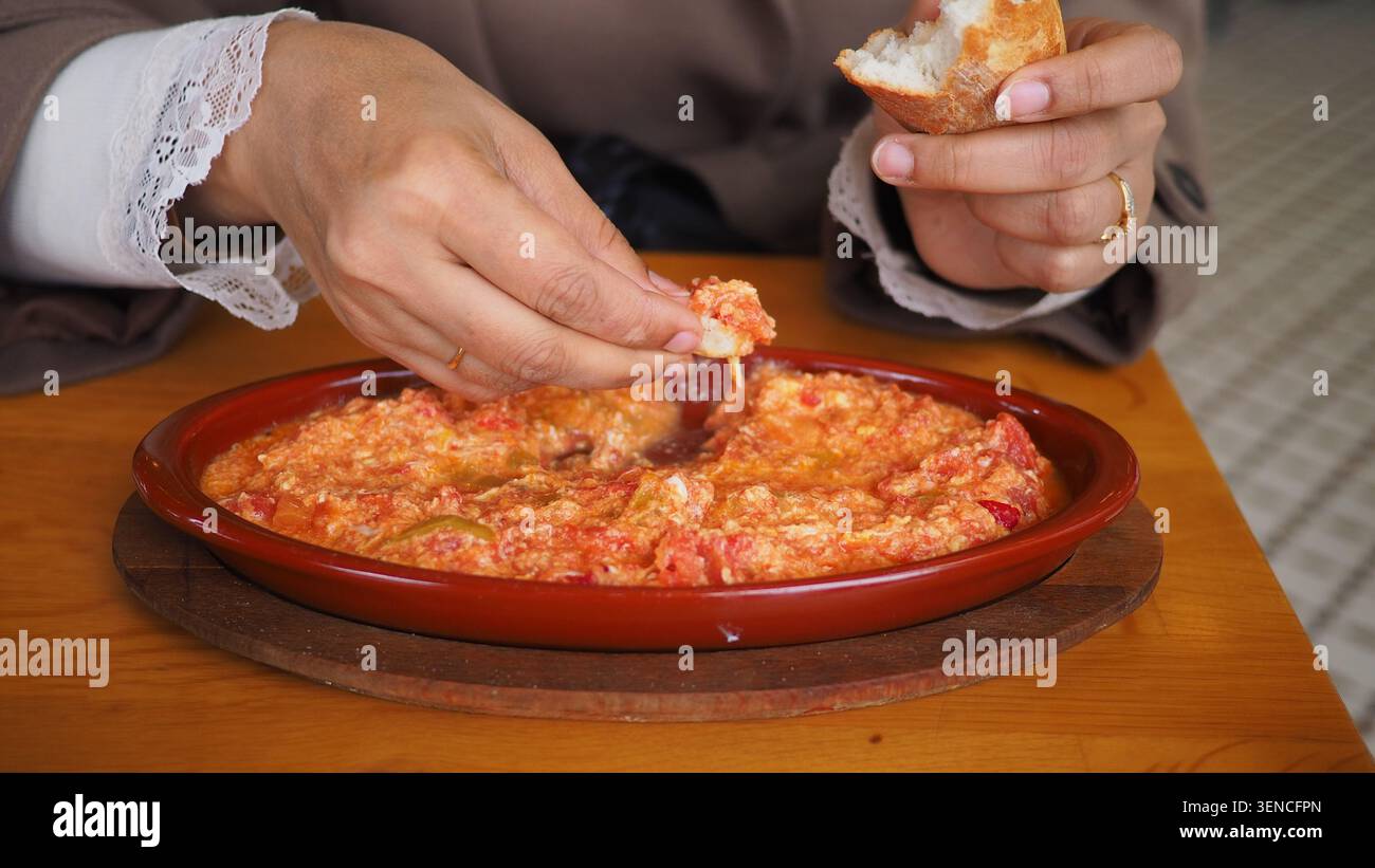 Una donna mangia una menemen turca con del pane in un ristorante Foto Stock