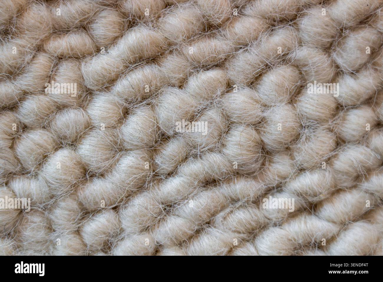 Vista macro delle fibre di lana lavorata a maglia spessa, sfondo in tessuto neutro caldo per design di interni e concept di moda Foto Stock