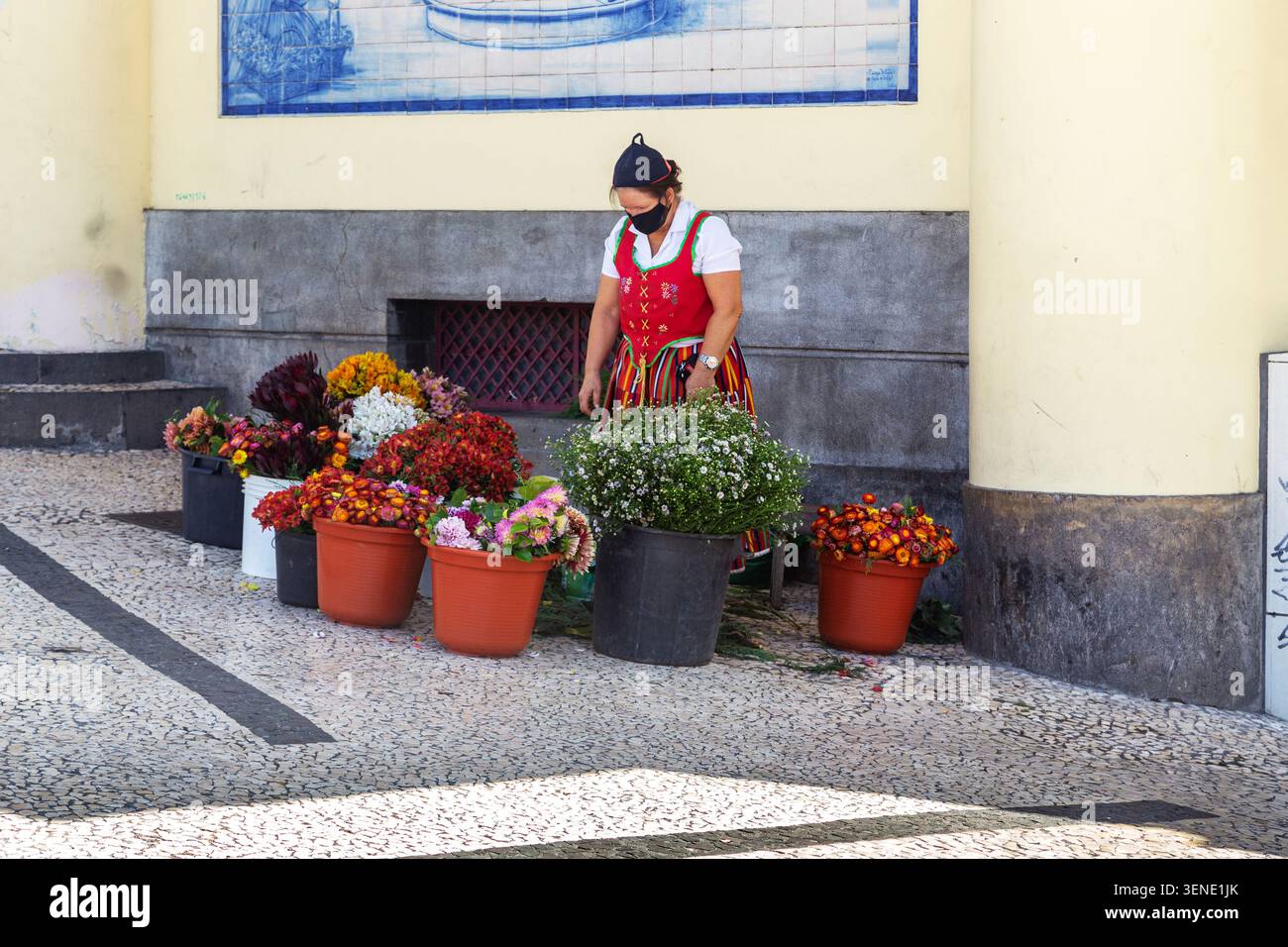 FUNCHAL, PORTOGALLO - 20 AGOSTO 2021: Si tratta di un venditore di fiori nel tradizionale costume nazionale della regione di Madeira, che vende all'ingresso della t Foto Stock