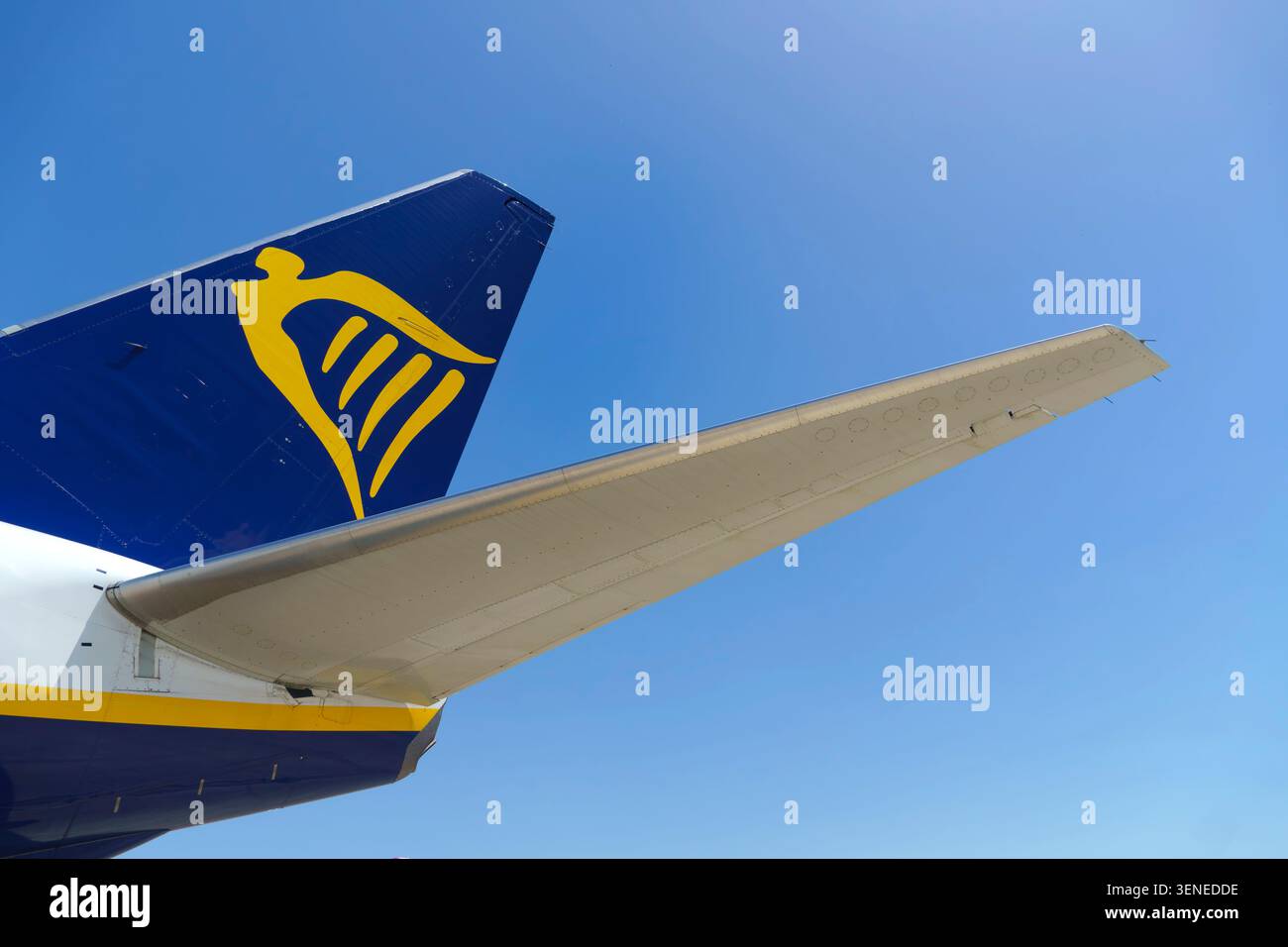Primo piano di una pinna di coda di un aereo Ryanair che mostra il logo dell'arpa gialla contro un cielo azzurro Foto Stock