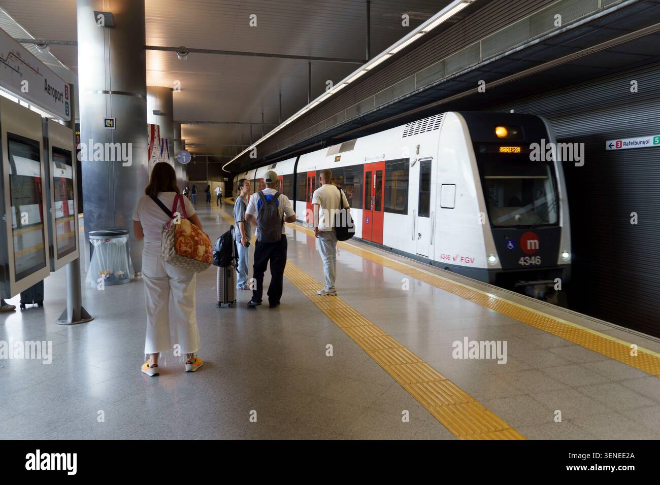 I passeggeri aspettano sul binario alla stazione della metropolitana Valencia Aeropuerto mentre arriva un treno Foto Stock
