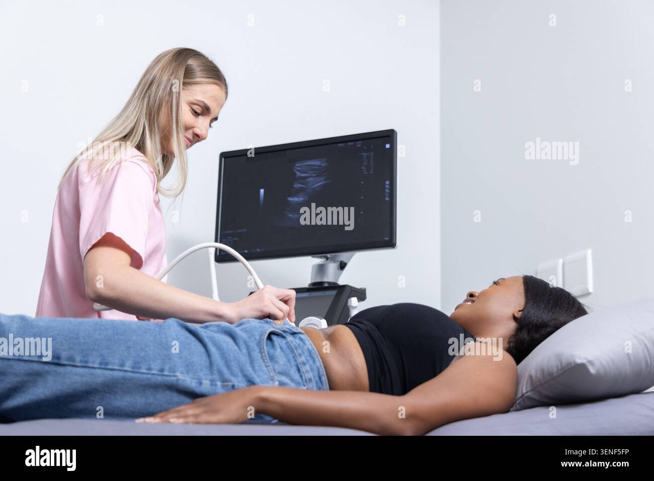 Ecografista che esegue la scansione di pazienti afroamericani con sonda nella sala esame con parte superiore nera Foto Stock
