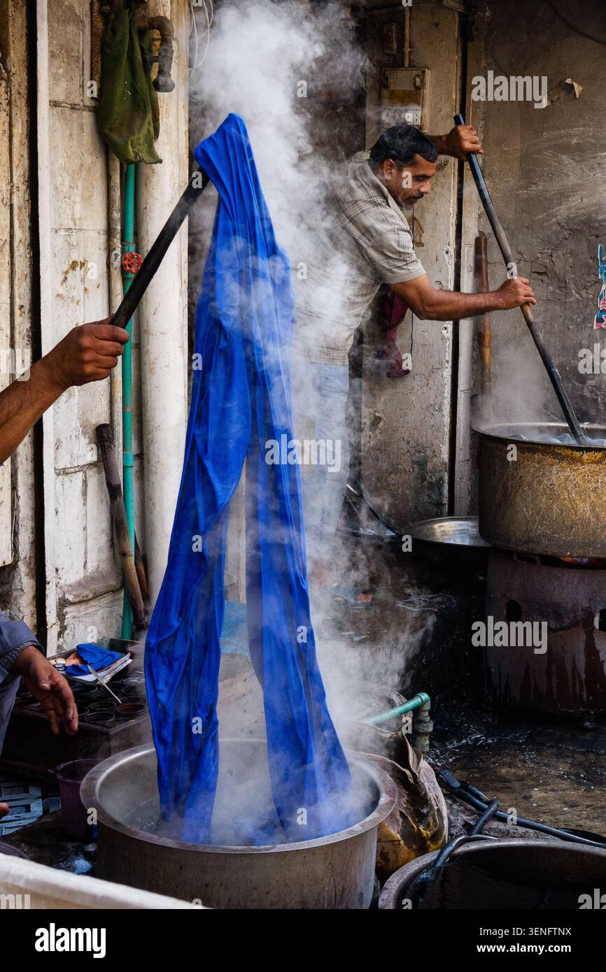Il tessuto viene sollevato dai lavoratori da una tintura per bucato a vapore. Foto Stock