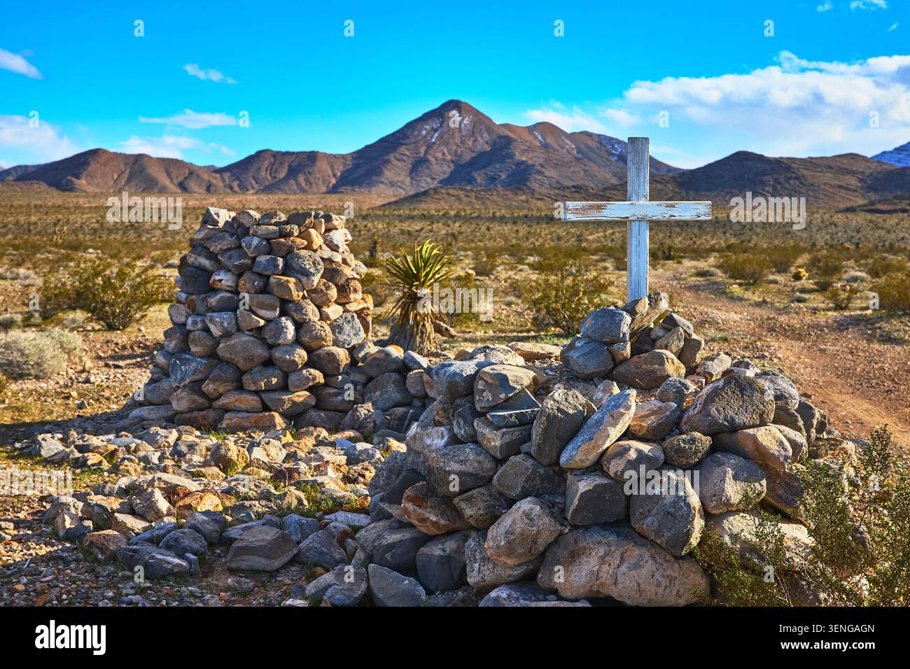 Tomba rustica di pietra con Croce Bianca nel deserto del Nevada con il Monte Charleston sullo sfondo Foto Stock
